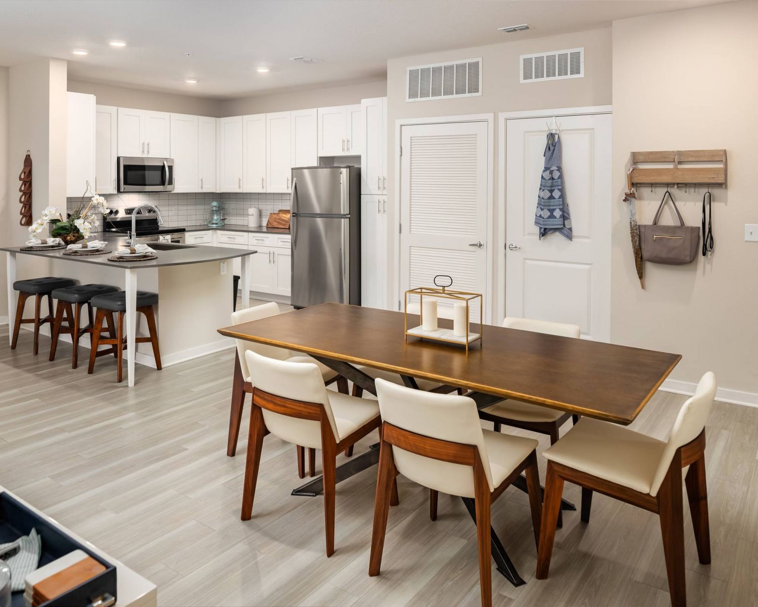 Shadetree Apartments with Modern kitchen and dining area with wood accents, white cabinets, and stainless steel appliances.