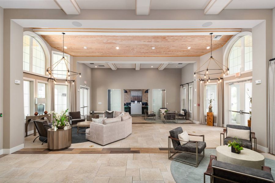 Shadetree Apartments with Modern, spacious lounge with neutral tones, armchairs, sofas, large windows, and decorative lighting fixtures.