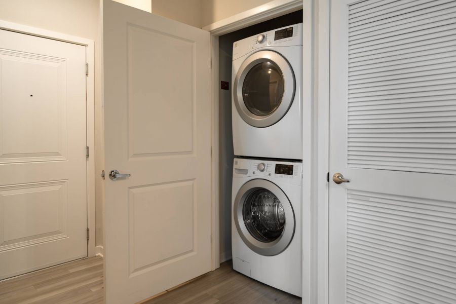Shadetree Apartments with Stacked washer and dryer inside a small closet with doors partially open.