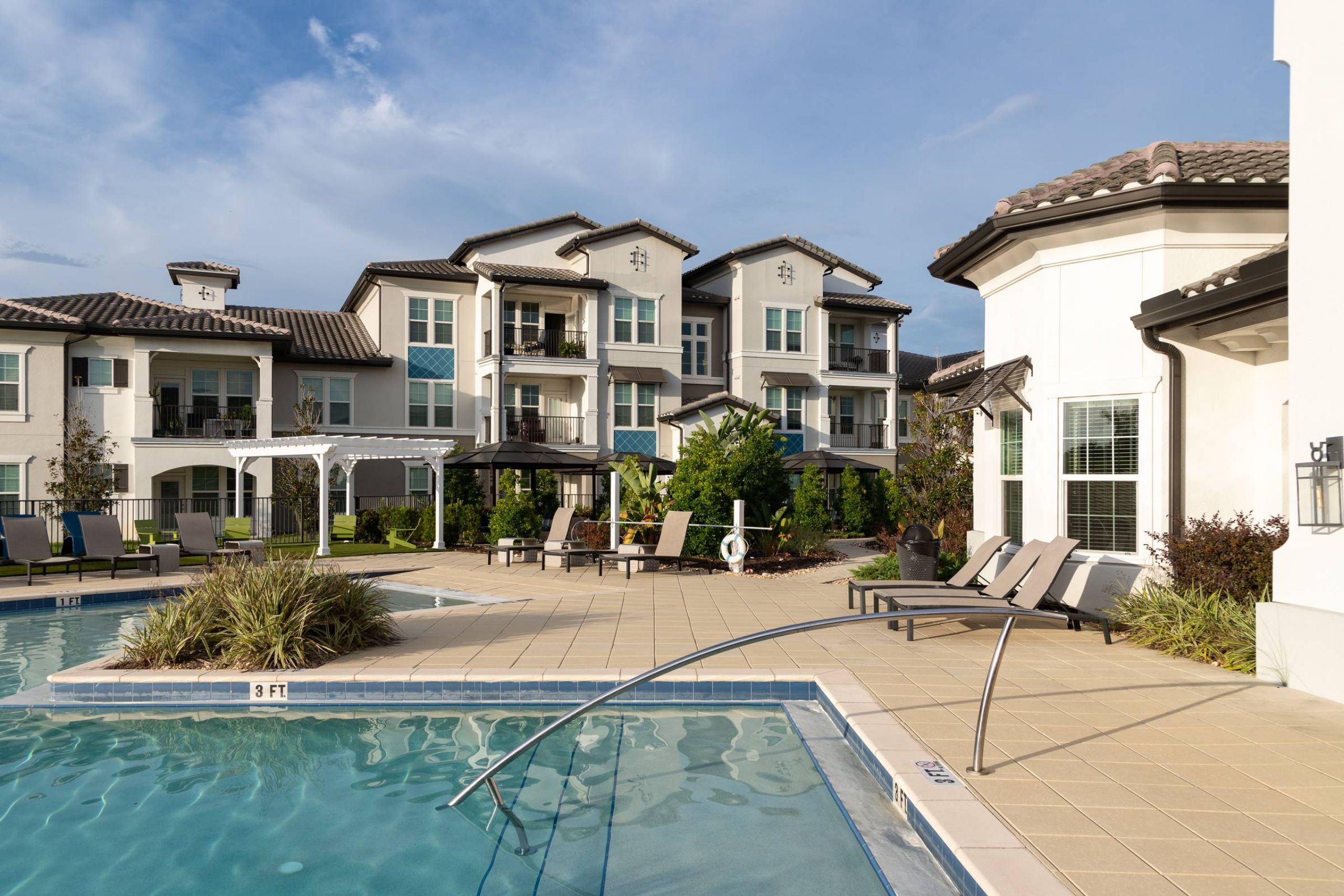 Shadetree Apartments with Modern apartment buildings with balconies overlooking a pool area with lounge chairs and landscaping.