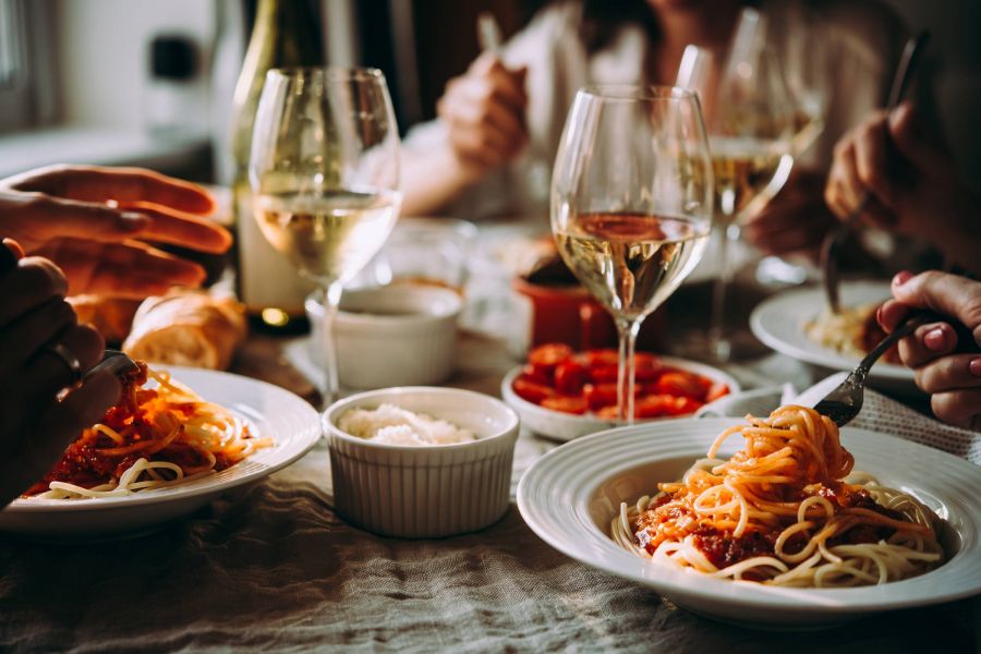 Shadetree Apartments with Friends having a pasta dinner at home of at a restaurant.