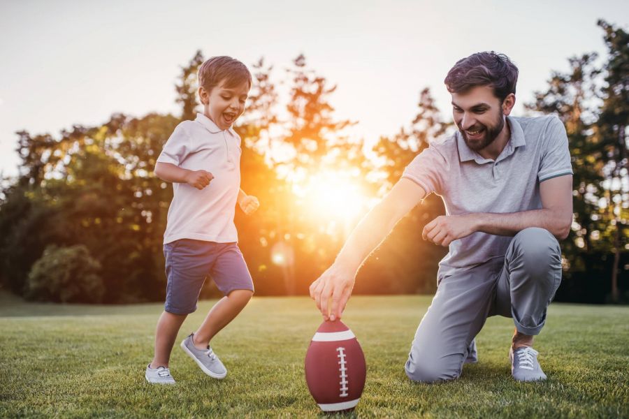 Shadetree Apartments in Ruskin, FL with a dad playing American football with his son at a park