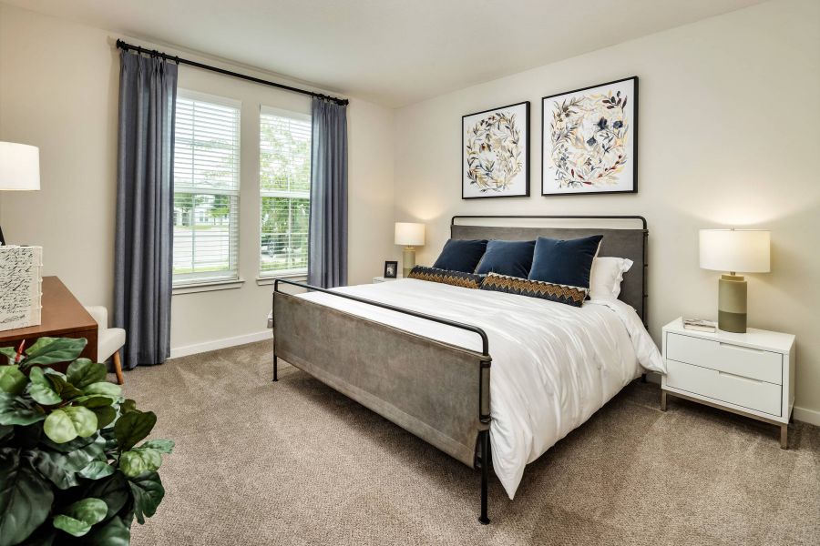 Shadetree Apartments with Modern bedroom with a metal bed, white bedding, two nightstands, and botanical art above the bed.